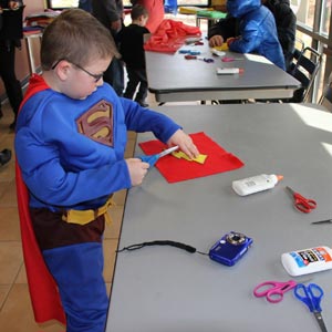Child in Superman costume working on arts and crafts