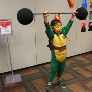 Child in turtle costume lifting fake weights